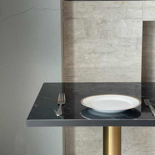 Top side view of a black marble table featuring elegant golden leg