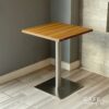 Isometric view of an oak top table featuring sturdy metal leg, highlighting its modern design