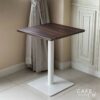 Isometric view of a walnut top table featuring square white leg