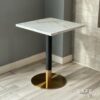 Isometric view of a white marble table featuring striking black and gold leg, showcasing a modern design