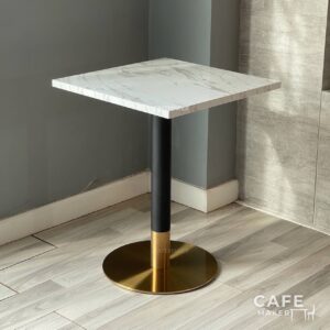 Isometric view of a white marble table featuring striking black and gold leg, showcasing a modern design