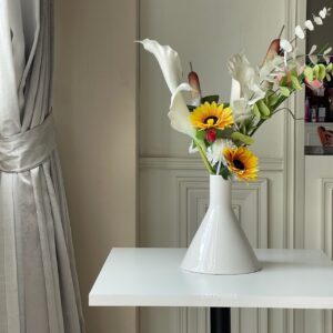 White top table with round leg, decorated with a flower arrangement