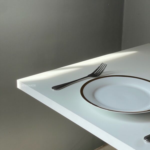 Top side view of a white top table with square metal leg