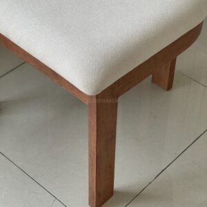 Close-up view of the leg of a parawood dining chair with a white cushioned seat