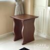 Isometric view of a walnut parawood cube table with wave-style legs