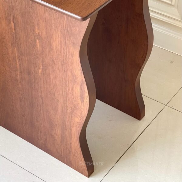 Close-up view of the wave-style leg of a walnut parawood cube table