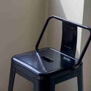 Close-up view of a black metal stool with backrest