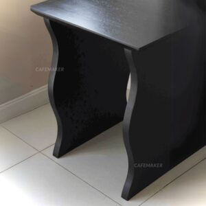 Close-up view of a black parawood cube table with wave-shaped legs