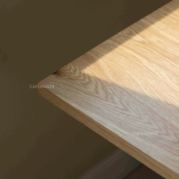 Close-up view of an oak top table with white square leg