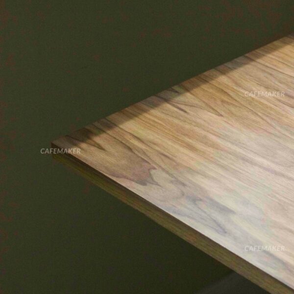 Close-up view of a walnut top table with square metal leg