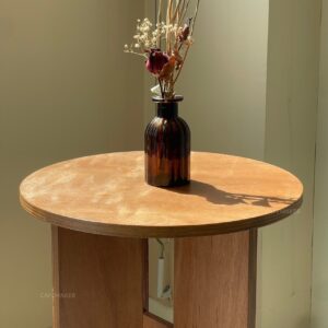 round plywood table with natural finish decorated with flower vase