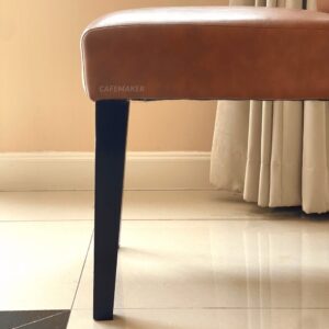 close-up of wooden leg on orange cushion chair showing joint and finish detail